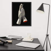 Framed Poster Art of Shireen Renee's "AEQ" original oil painting depicting two mannequin hands holding each other suspended in space against a black background. The artwork is hanging on a plain white wall in an office with a black desk and a black lamp.