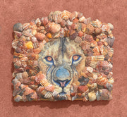 "Leo" is a mixed media art piece by Shireen Renee depicting the oil painting of a lion's face which is surrounded by a mane of real seashell fragments of orange, red and yellow hues.