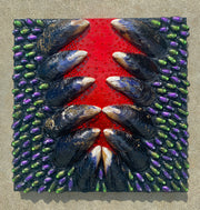 Close-up of a mixed media artwork by Shireen Renee, showing mussel shells, painted pistachio shells in purple and green, and rhinestones arranged on a wood panel with a red stripe down the center.