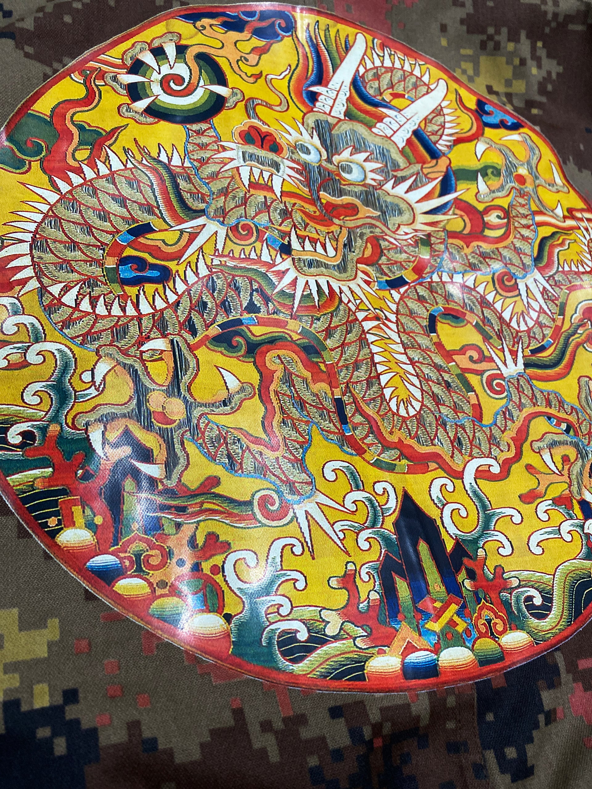 Detail image of the dragon medallion artwork from 16th century China printed on the back of a Chinese military camo jacket.