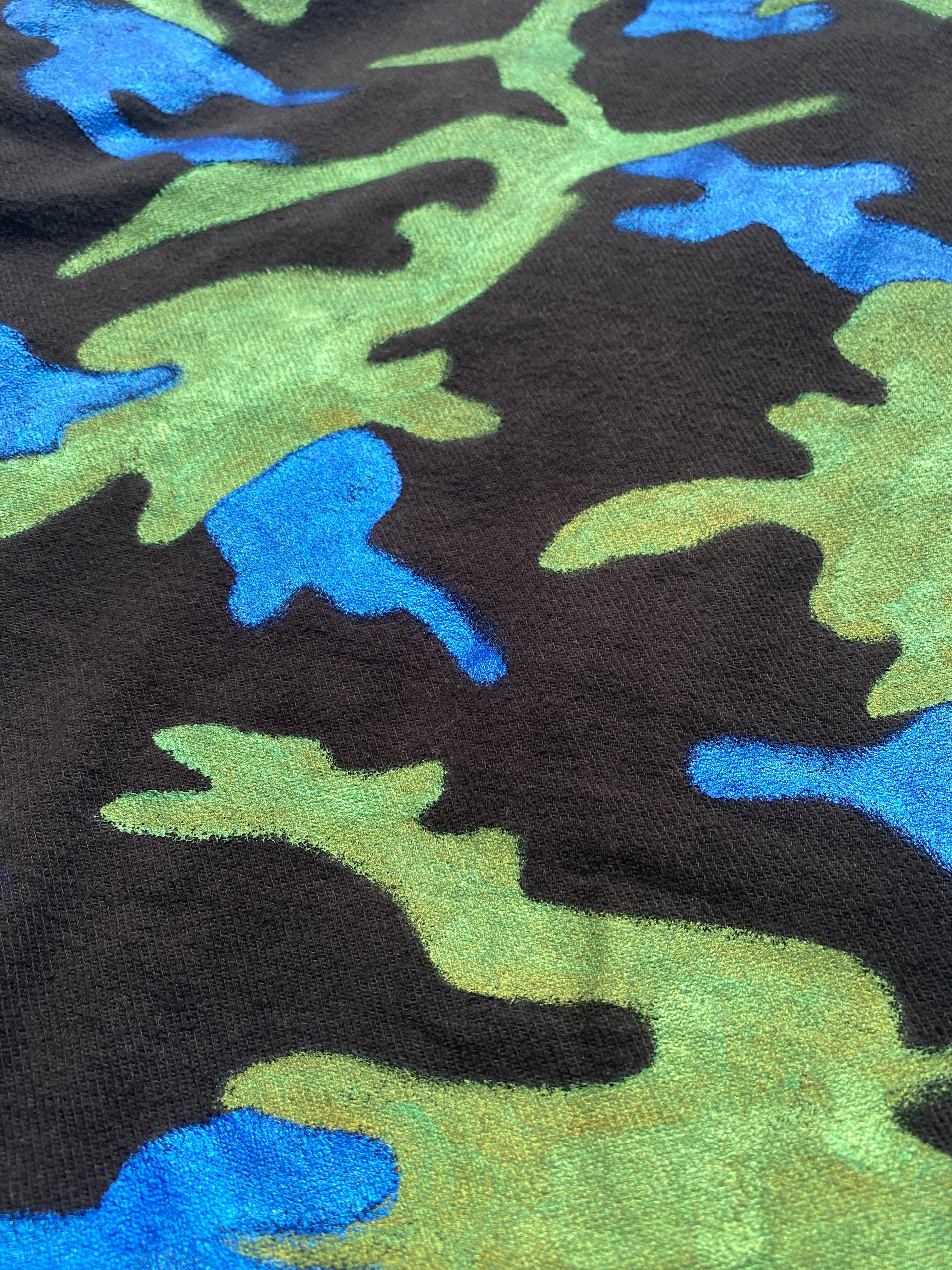 Detail view the Art Of Uniformity "Camo Planet" organic black brushed cotton unisex jacket with blue and green hand-painted camo print.