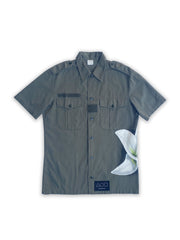 Art of Uniformity French vintage button front army shirt in olive green with a giant hand-painted white lily on the wearer's left side.