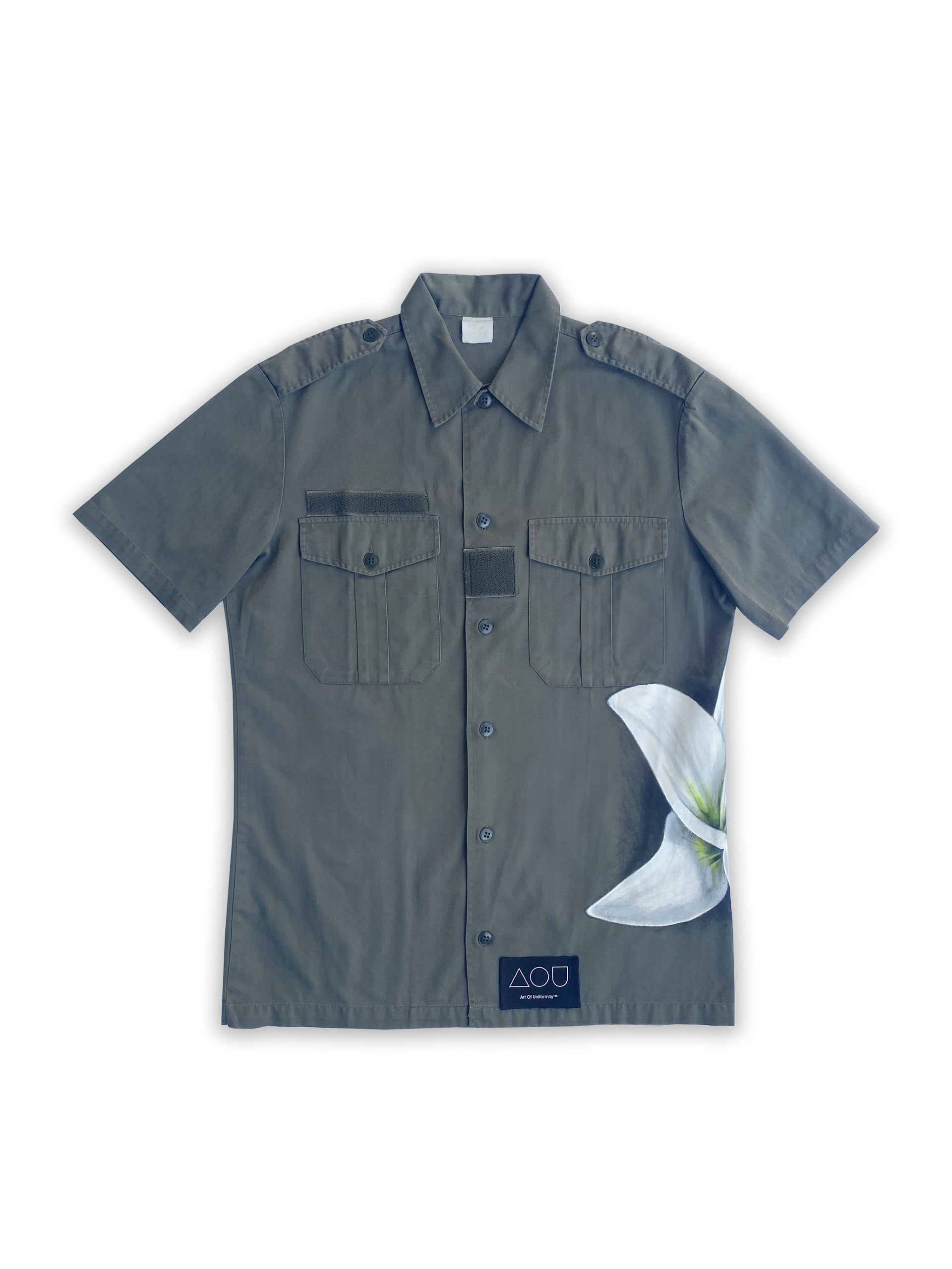 Art of Uniformity French vintage button front army shirt in olive green with a giant hand-painted white lily on the wearer's left side.