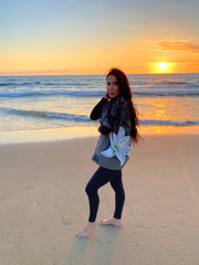 Model standing in front of an ocean sunset wearing a French vintage army shirt with a giant white lily painted on the side.