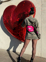 Model wearing a vintage American camo jacket with hand-painted pop lip art standing in front of a giant red heart.