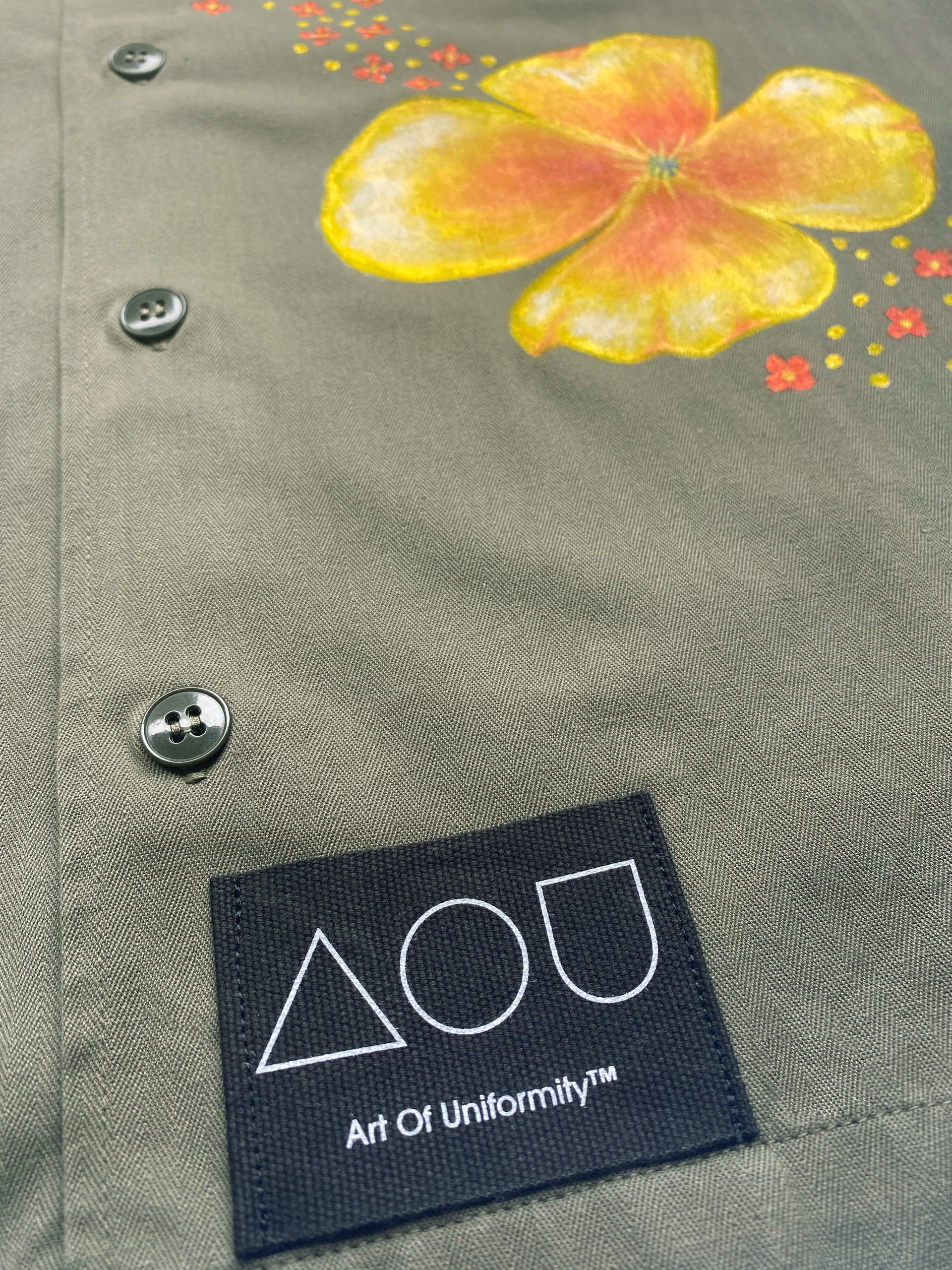 Vintage French 90's button down army shirt in olive green with large hand-painted orange-yellow poppies on the front and back.