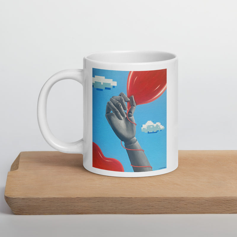 White glossy ceramic mug with original art "The Game" depicting a mannequin hand holding a red balloon against a sky blue background with floating pixelated clouds.